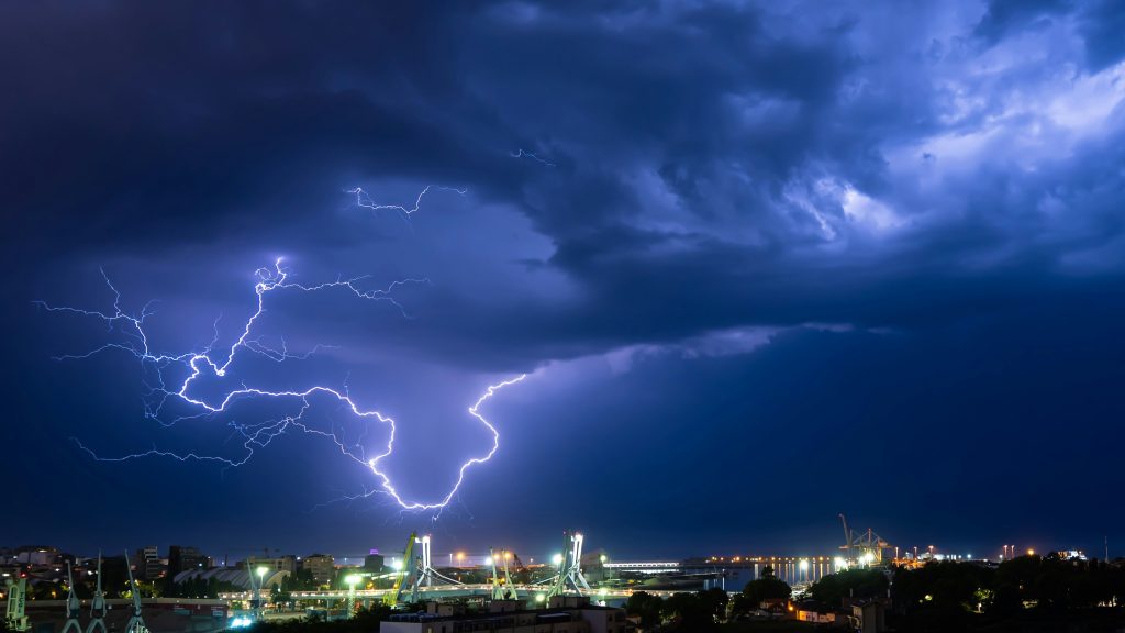 cityscape under a stormy sky, dramatically lit by a bolt of lightning in Leça da Palmeira, Porto district, Portugal