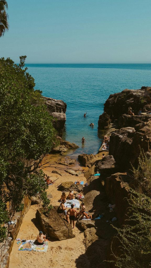 Cascais Beach with blue ocean and people sunbathing, to escape heat wave in Portugal